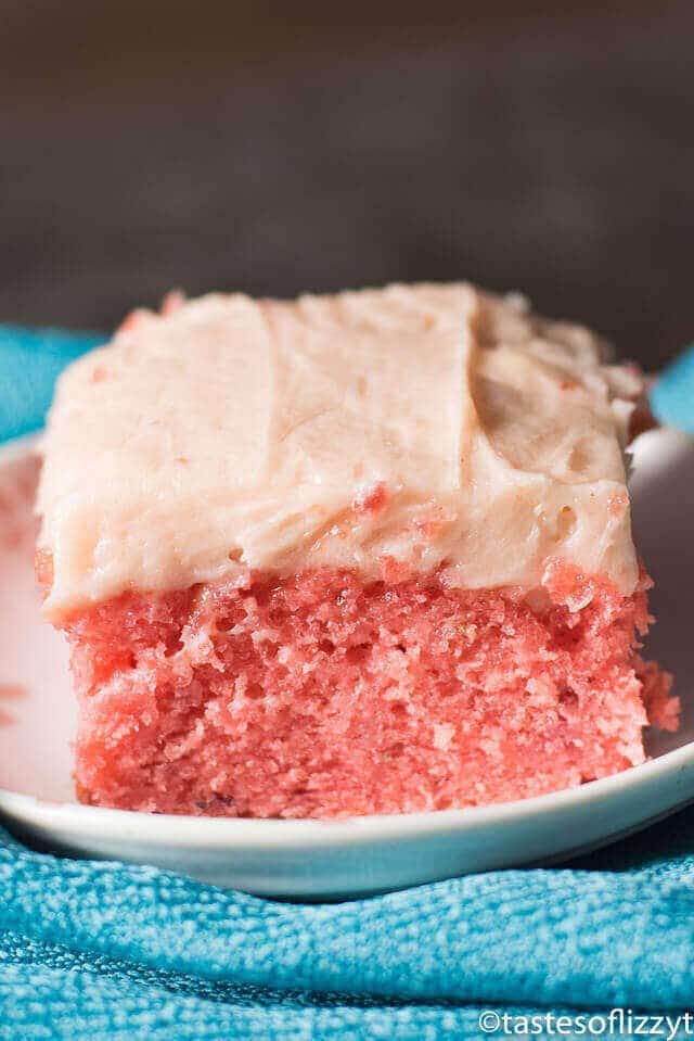 A close up of a piece of cake on a plate with strawberry frosting