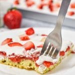 A close up of a piece of cake on a plate, with Strawberries
