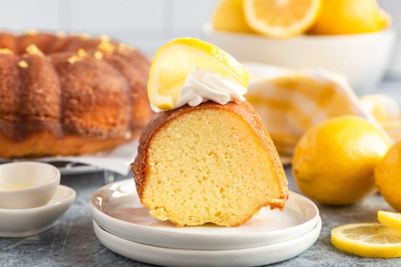 a piece of lemon pound cake on a plate with lemon and whipped cream