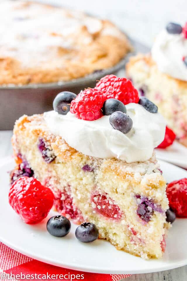 A close up of a piece of cake on a plate, with fresh berries