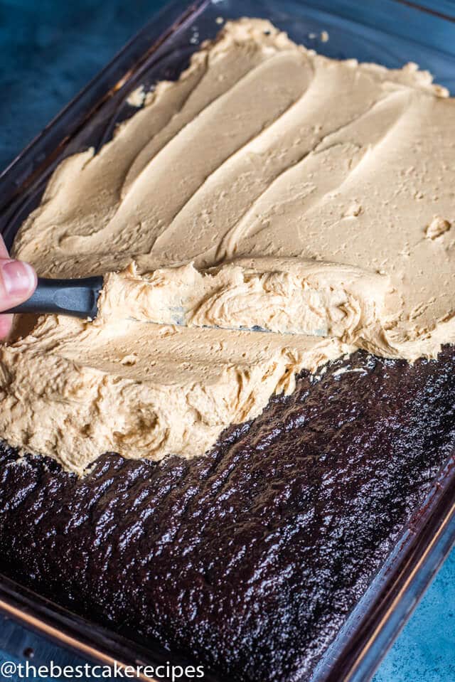 knife spreading peanut butter frosting on a chocolate cake
