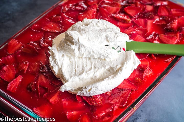 spreading cool whip over a strawberry cake