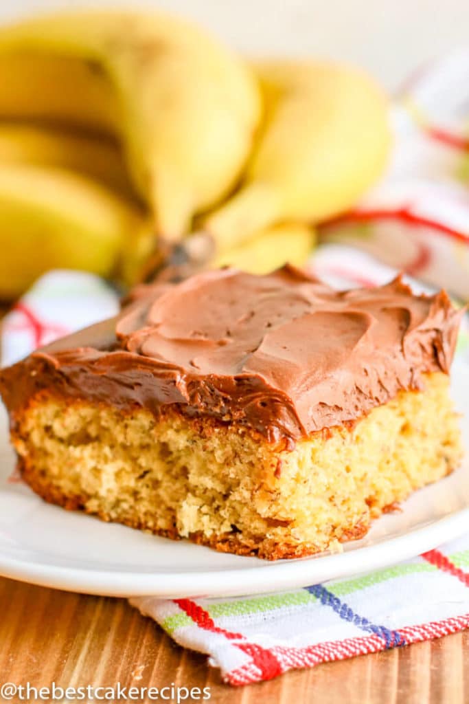 A piece of cake on a plate, with Banana cake and Chocolate frosting