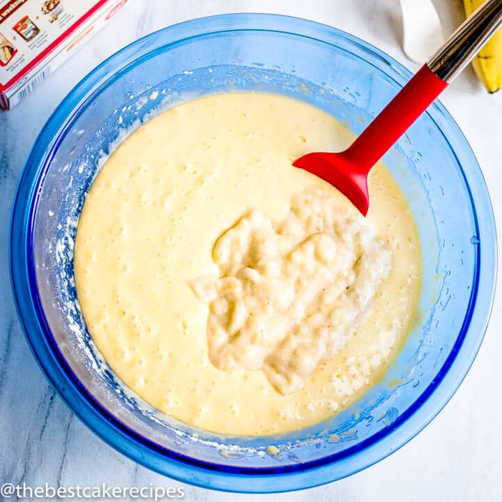 cake batter in a bowl with unmixed mashed bananas