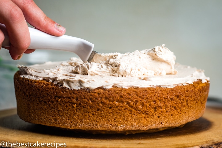 spreading cinnamon buttercream on a cake