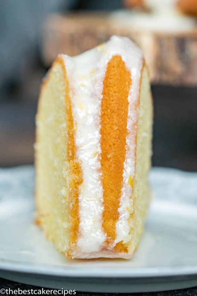 A close up of a slice of cake on a plate, with Lemon and glaze