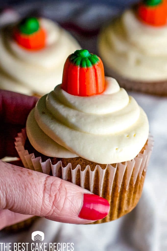 handing holding a frosted Pumpkin Cupcakes