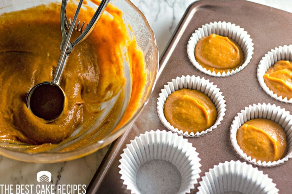 unbaked pumpkin cupcake batter in a bowl and muffin cups
