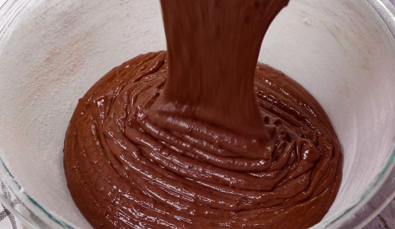 chocolate cake batter pouring into a pan