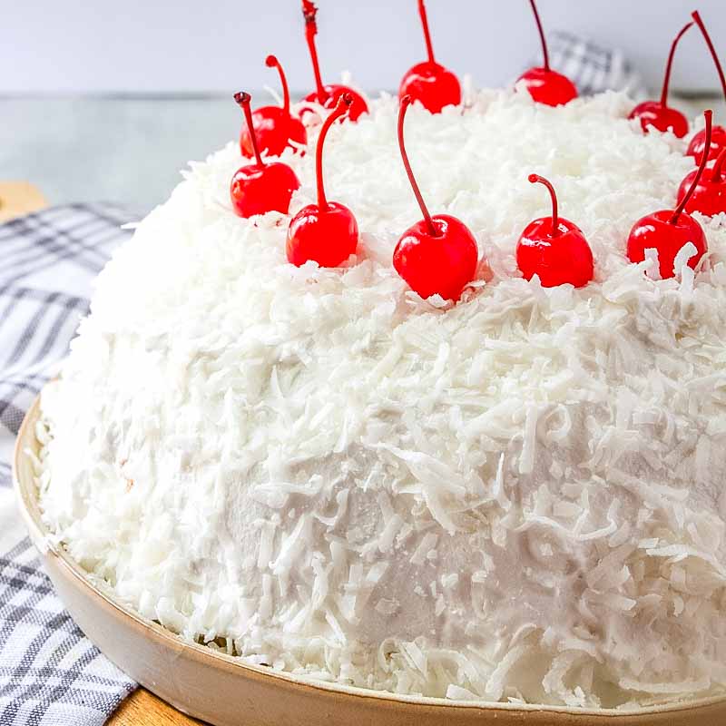 coconut no bake cake with cherries on a cake plate
