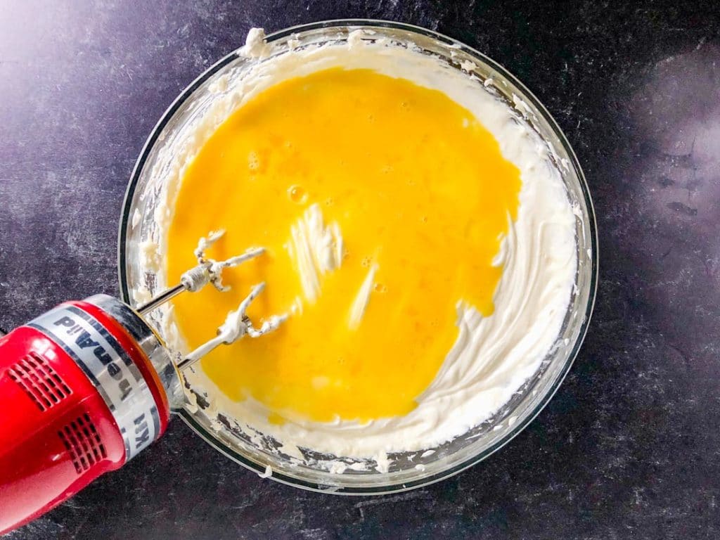mixing beaten eggs into cheesecake batter