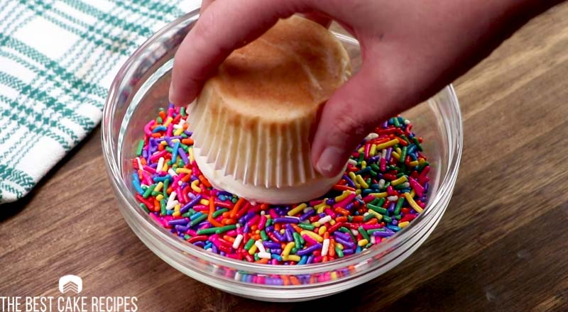 dipping a cupcake in sprinkles
