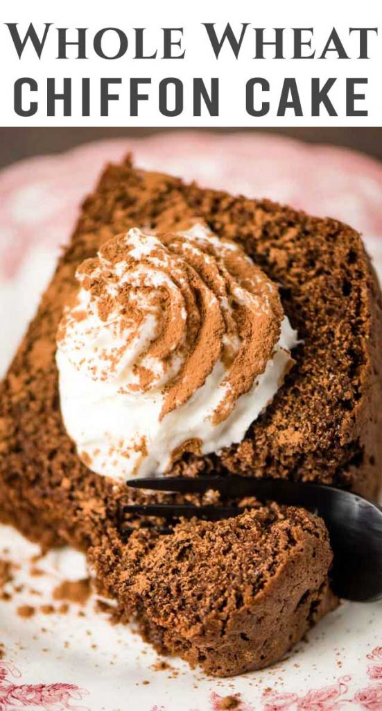 A piece of chocolate cake on a plate, with whipped cream and cocoa powder