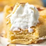 almond butter cake on a plate with whipped cream and bite out of it