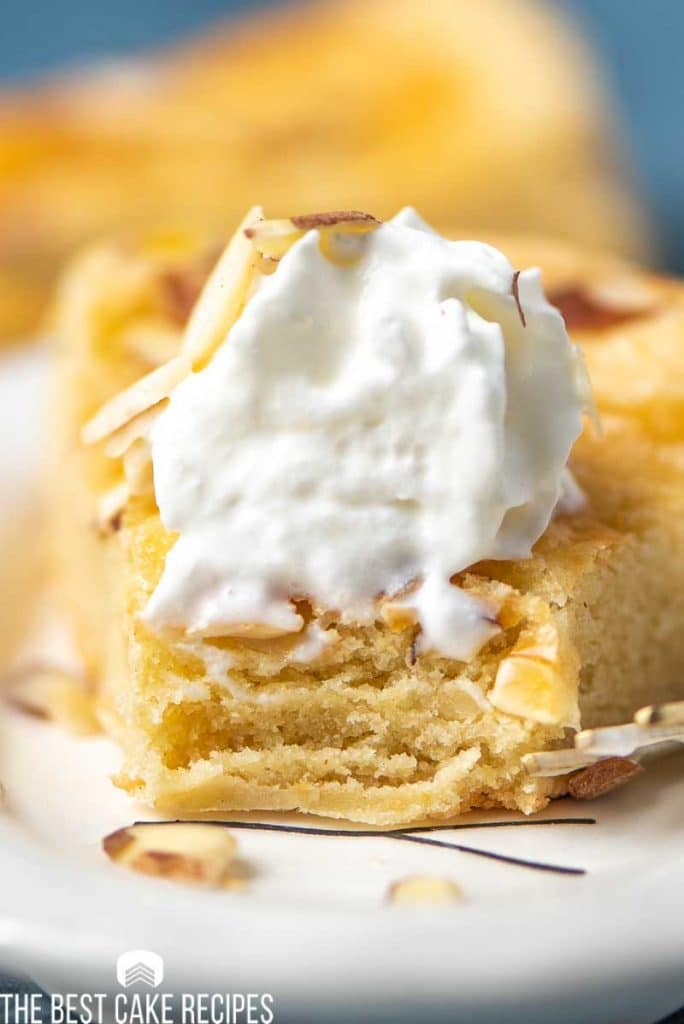 closeup of dutch butter cake  on a plate with whipped cream and bite out of it