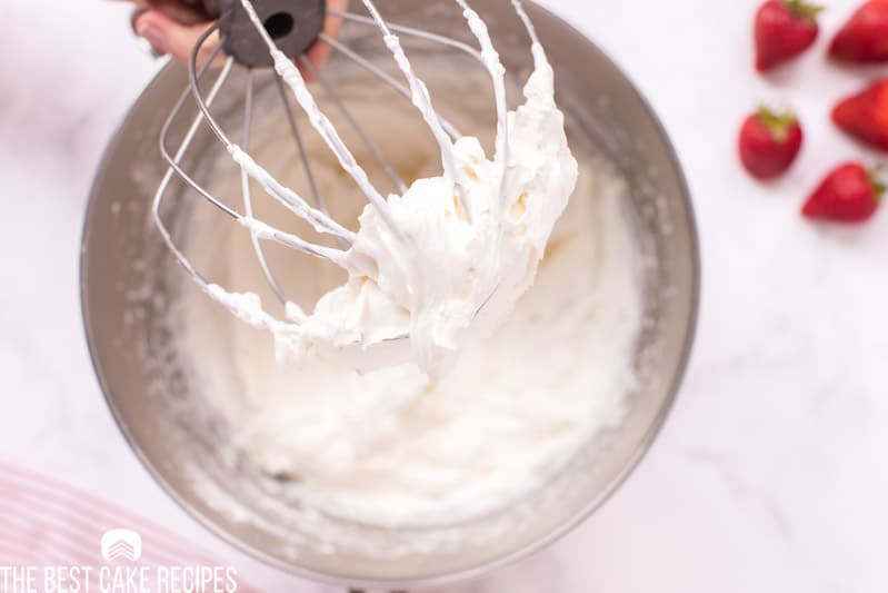 white whipped frosting in mixing bowl with whisk attachment