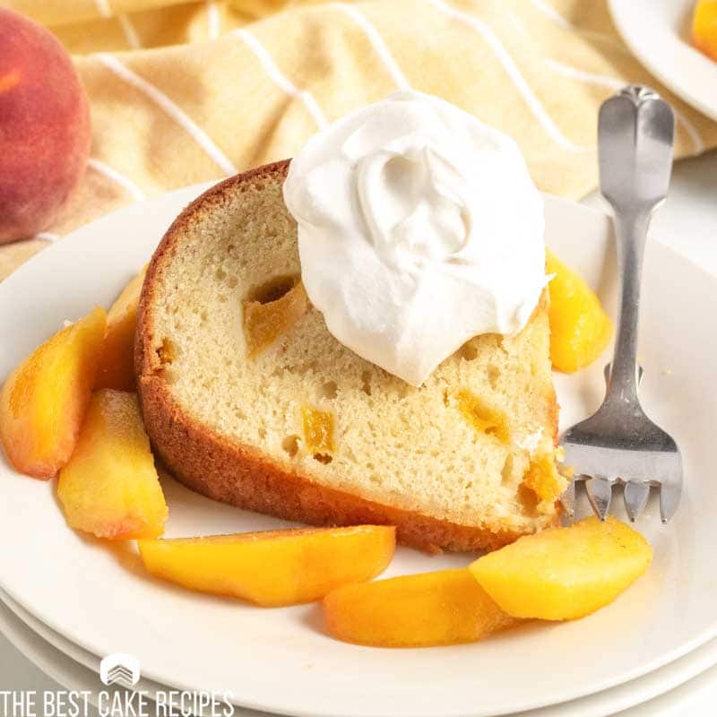 slice of peach pound cake on a plate with whipped cream