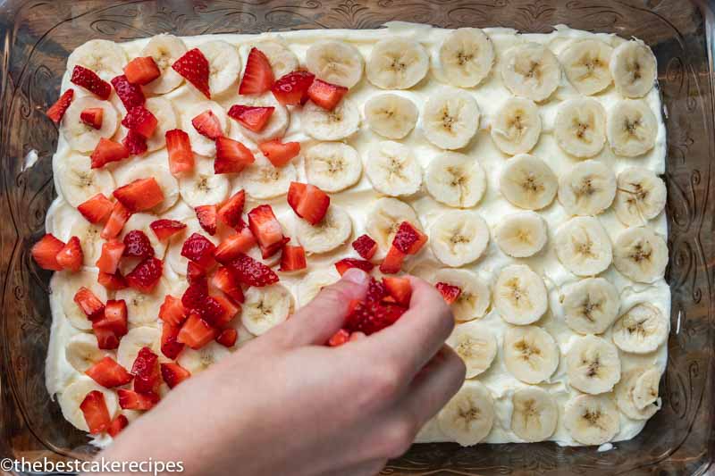 placing strawberries and bananas on a cake