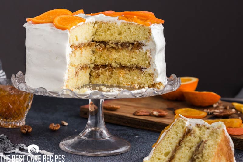 orange cake on a cake stand with one piece plated