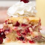 piece of cranberry pudding cake with whipped topping on a plate