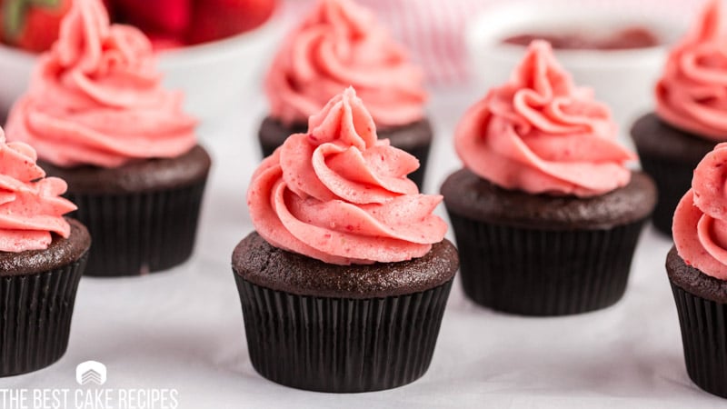 a set of chocolate cupcakes with strawberry frosting