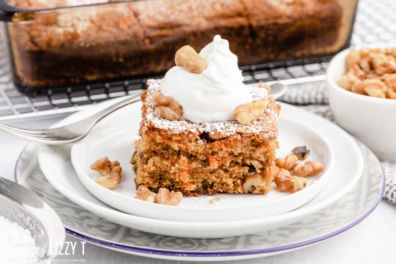 a piece of carrot cake on a plate with whipped cream and walnuts