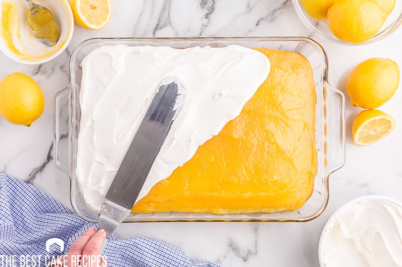 spreading cool whip on a lemon cake