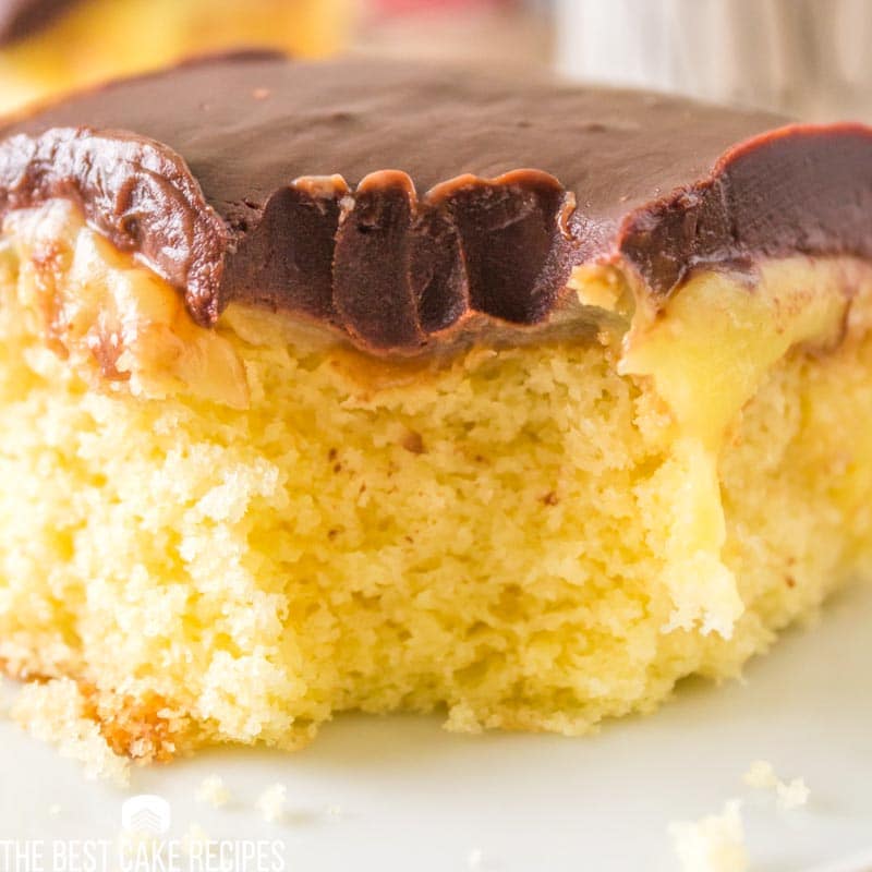 a piece of boston cream poke cake with a bite out
