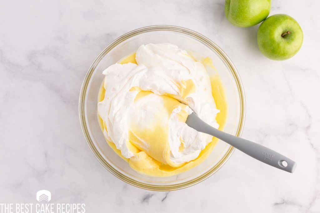 cool whip mixing into pudding in a glass bowl