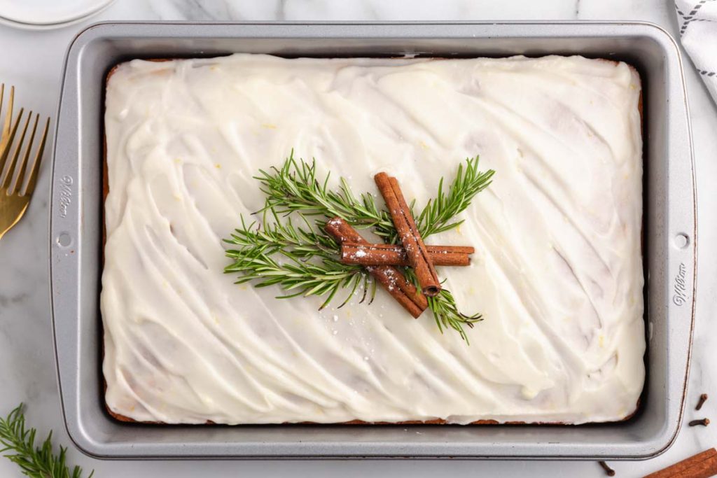 overhead view of a cake with cinnamon sticks and rosemary