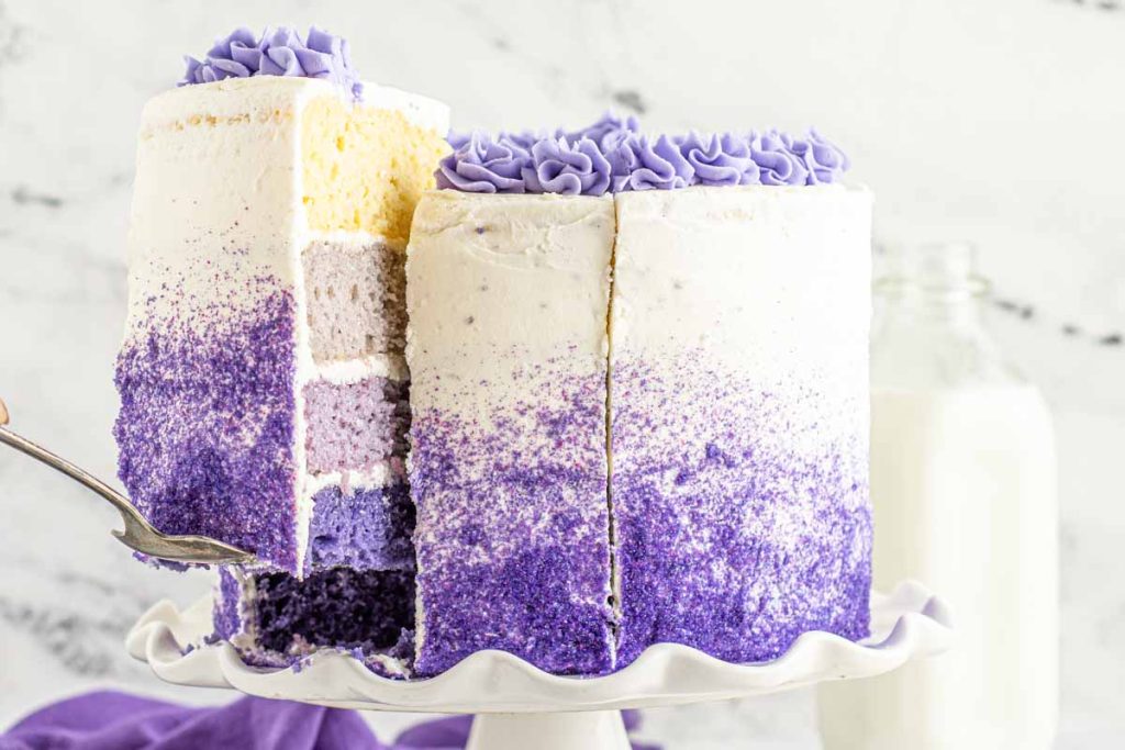 purple ombre cake with a spatula holding a slice of cake