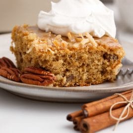 a piece of caramel coconut spice cake on a plate with whipped cream
