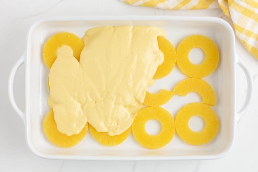 cake batter over pineapple rings in a baking pan