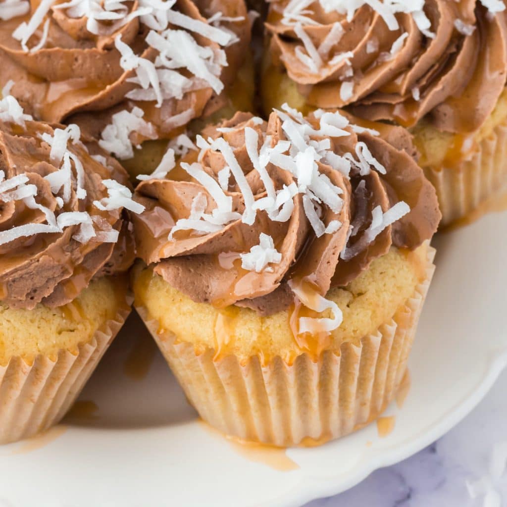 cupcakes sitting on a plate with coconut and caramel