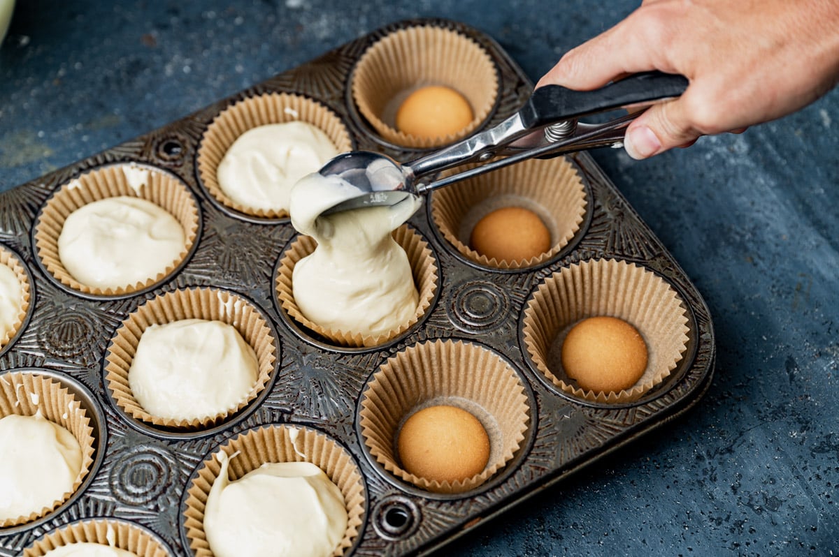 spooning cheesecake filling into muffin liners