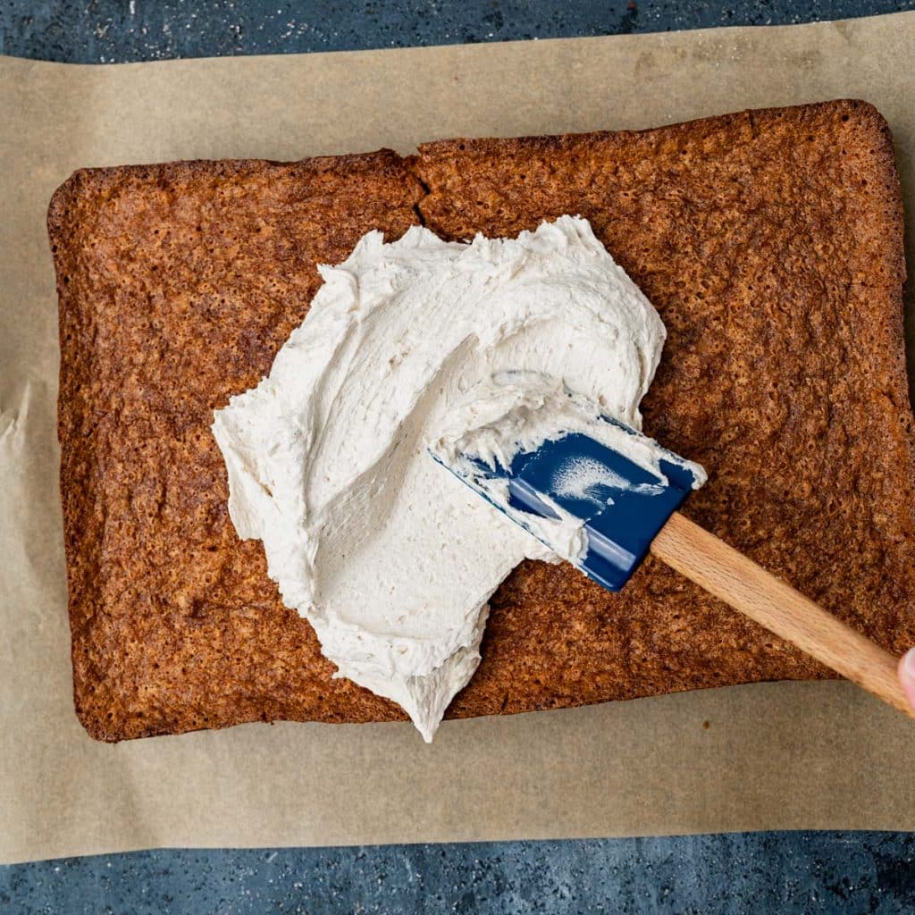 a spatula spreading frosting over a graham cracker cake