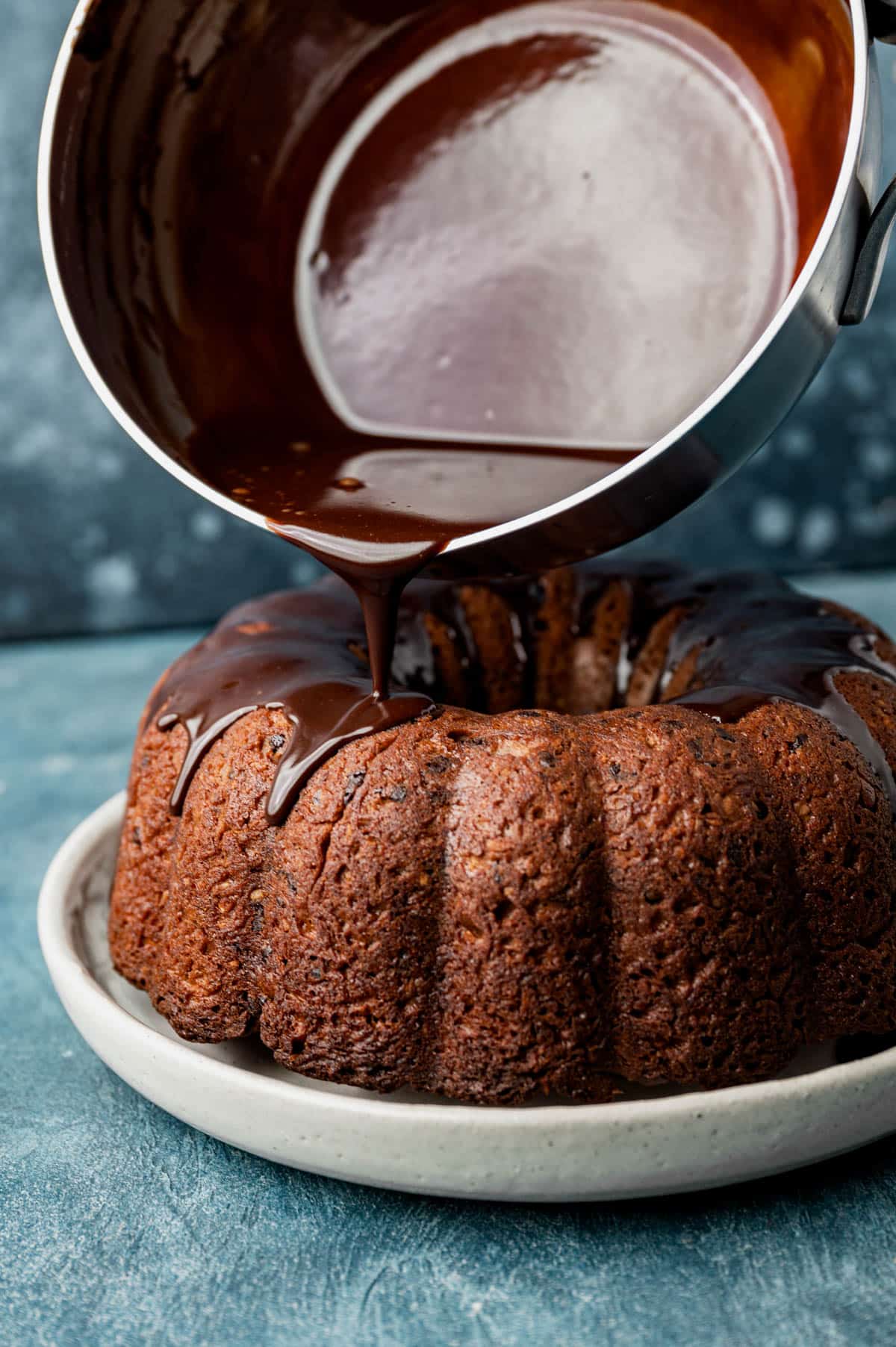 pouring fudge sauce over a chocolate bundt cake