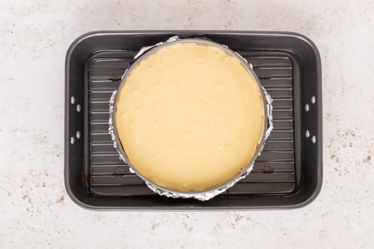 unbaked cheesecake in a springform pan sitting in a water bath