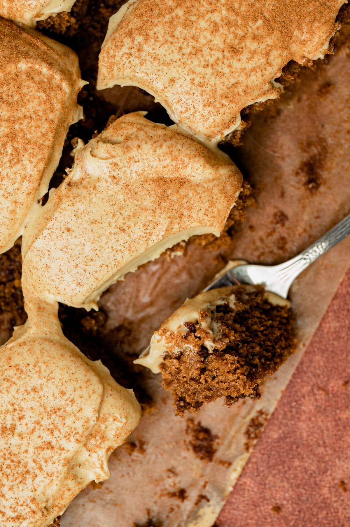 overhead view of gingerbread sheet cake on a table with a bite on a fork