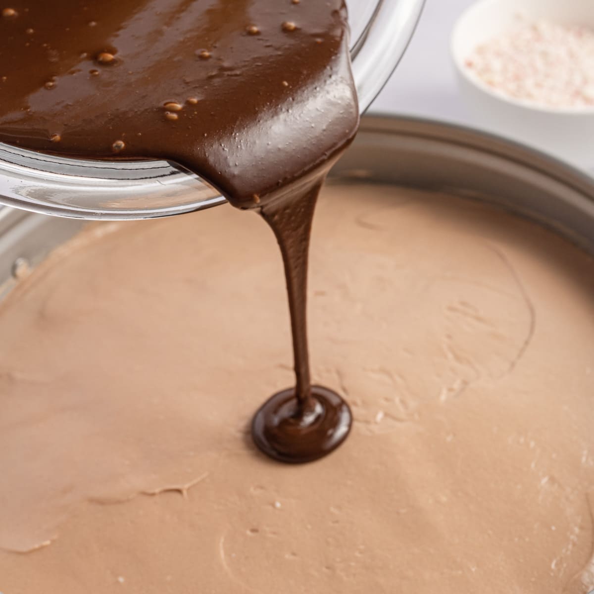 chocolate pouring over a peppermint no bake cheesecake