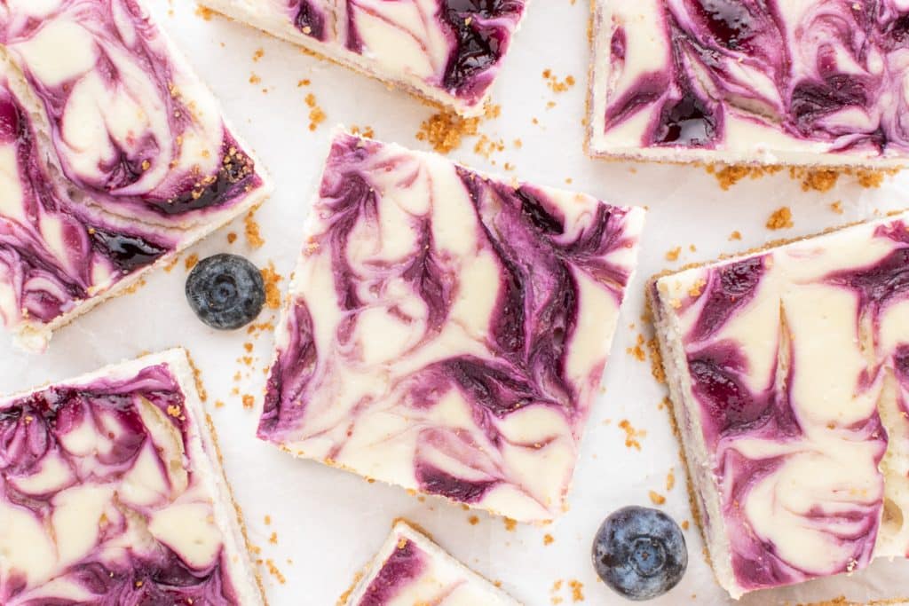 overhead view of cheesecake bars with blueberry swirled on top