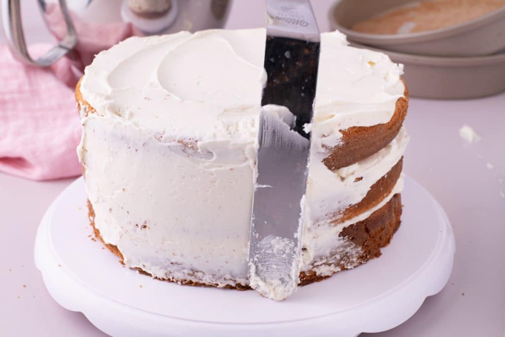 a spatula spreading frosting on a layer cake