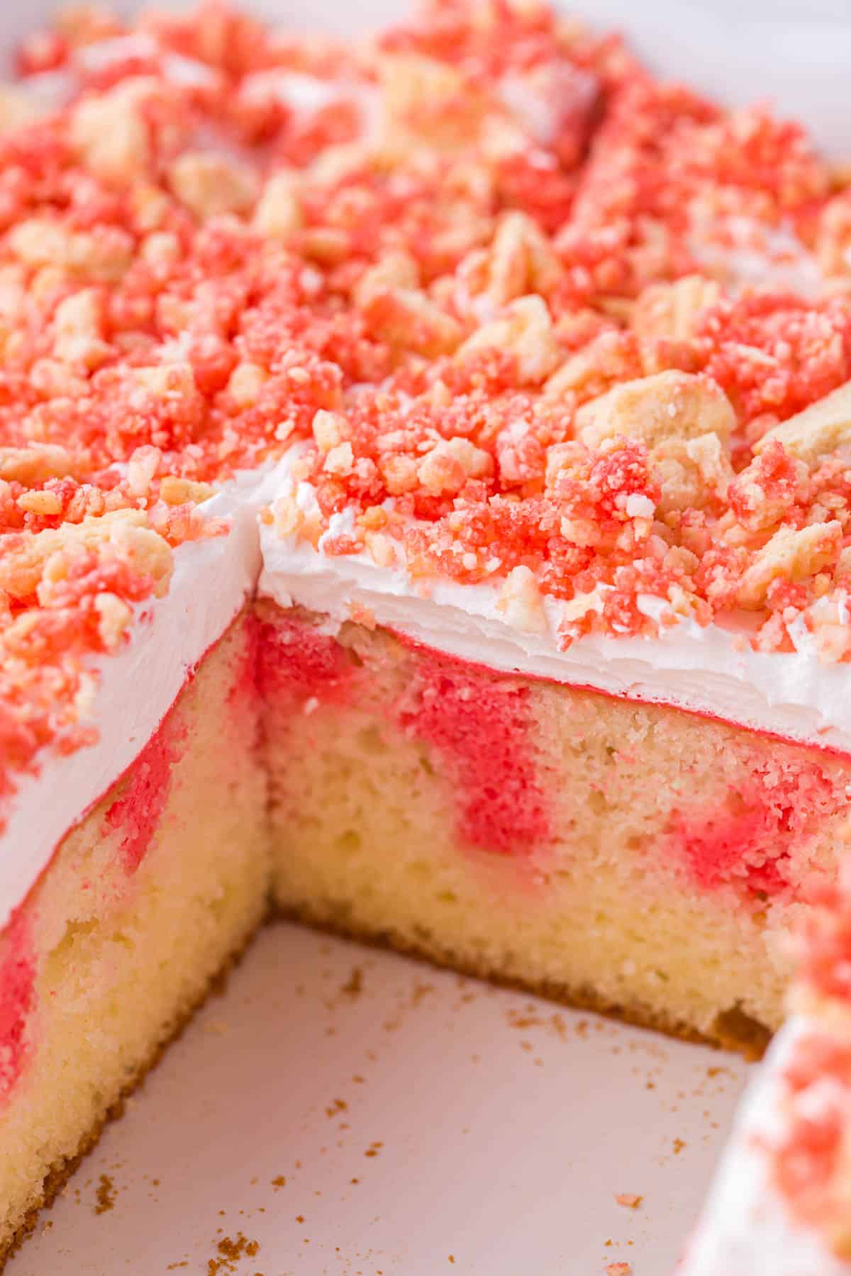 a sliced poke cake with strawberry crunch topping