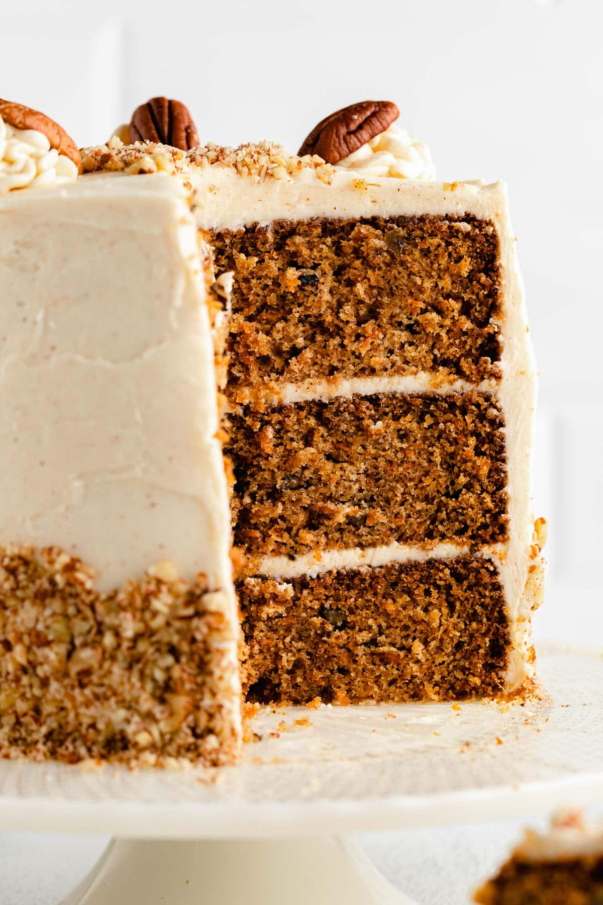 a ginger carrot cake on a cake plate with a large slice out