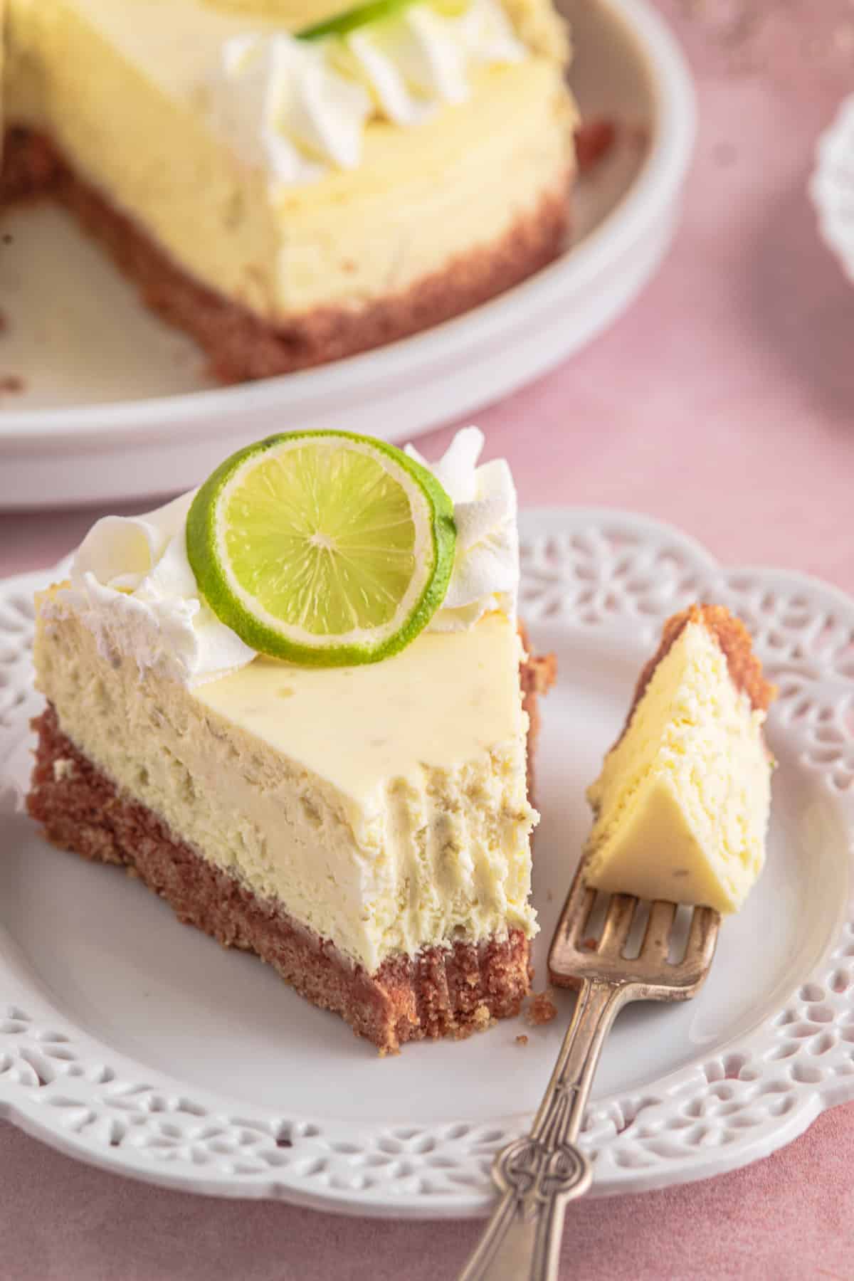 a slice of lime cheesecake with graham cracker crust on a plate with a fork
