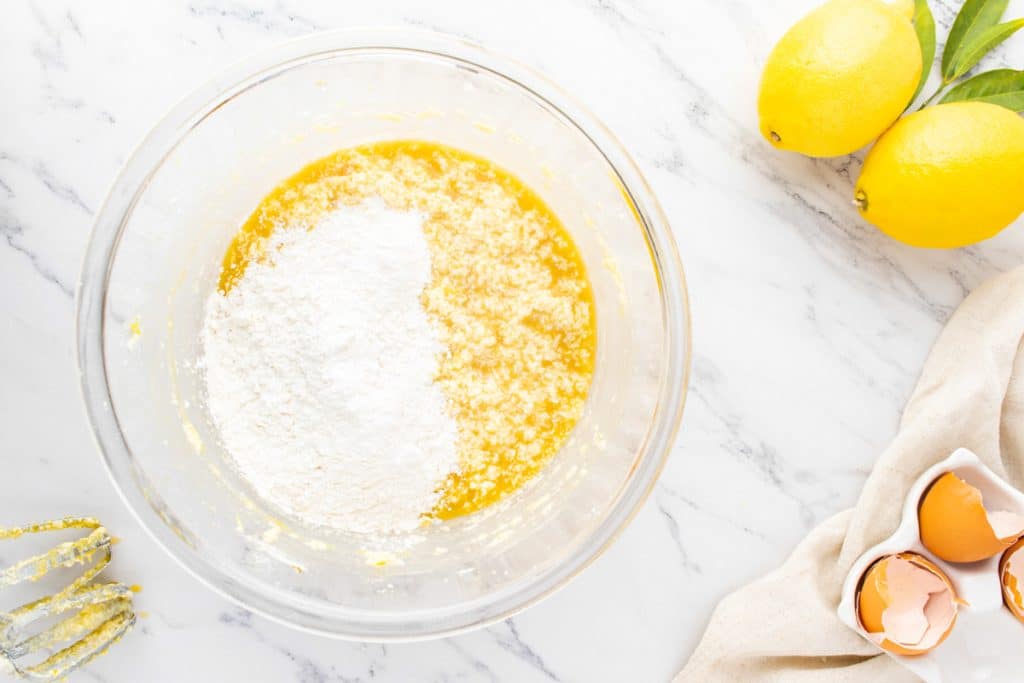 flour over butter sugar mixture in a bowl
