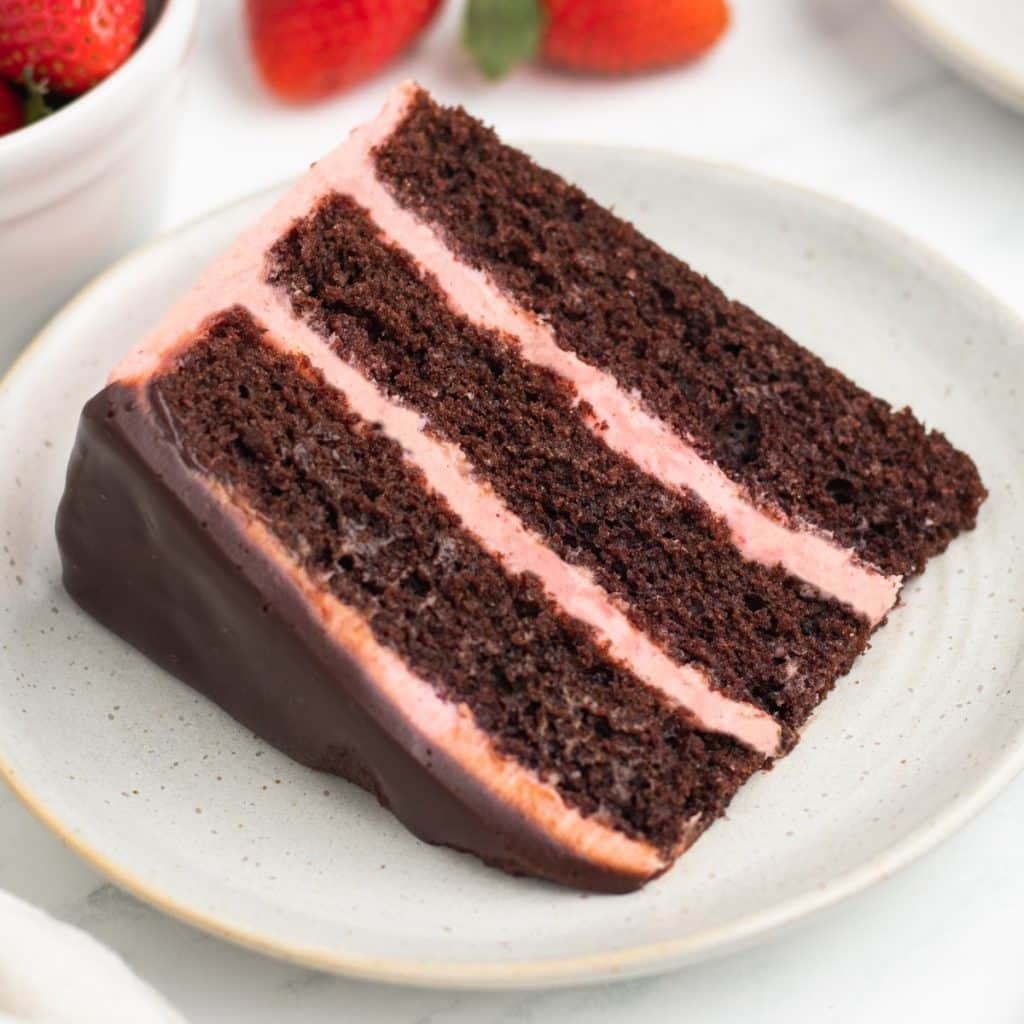 a piece of 3 layer chocolate strawberry cake on a plate