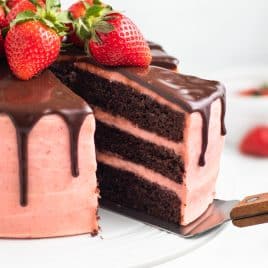 closeup of a slice of chocolate strawberry drip cake on a spatula