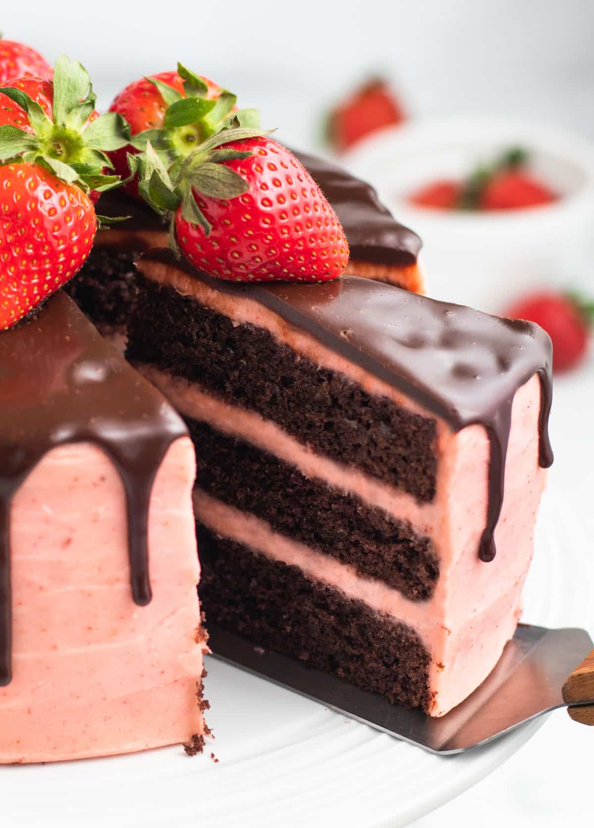 a slice of chocolate strawberry drip cake on a spatula