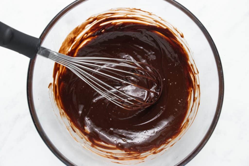 chocolate ganache in a glass bowl with a whisk